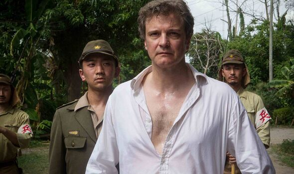 An individual dressed in a white shirt is walking while accompanied by two uniformed individuals standing behind him. They are i