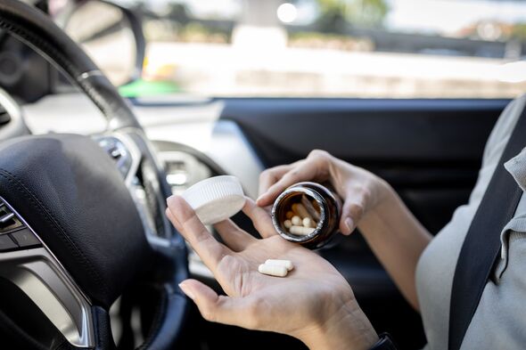 Woman pouring medicine capsule into her palm of hand,taking medication while driving a car,dangers of consuming certain drugs that can cause drowsines