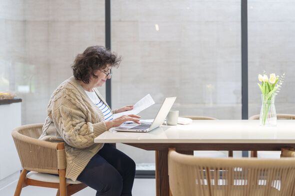 Senior women calculating their finances at home, reviewing financial statement paper and doing home accounting with laptop computer.