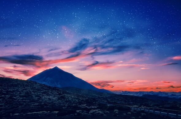 Silhouette of volcano del Teide against a sunset sky.