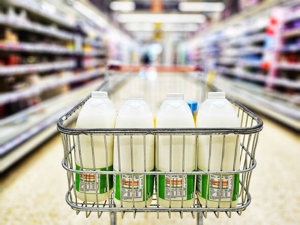 Fresh milk in the shopping cart in the dairy aisle of the supermarket. Focus on the milk with the aisle defocused beyond.