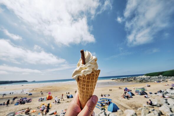 POV wide angle view of a hand holding Ice cream cone at Fistral Beach, Newquay on a sunny June day.