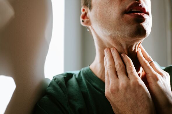 A man massages a sore neck / throat