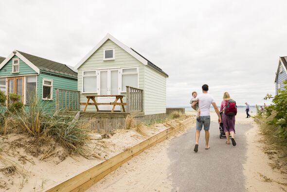 Beach huts at seaside in Dorset UK with young family on holiday