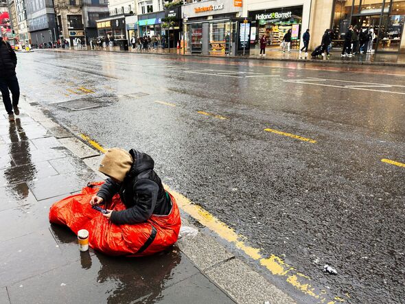 Homeless teenager in red sleeping bag rainy