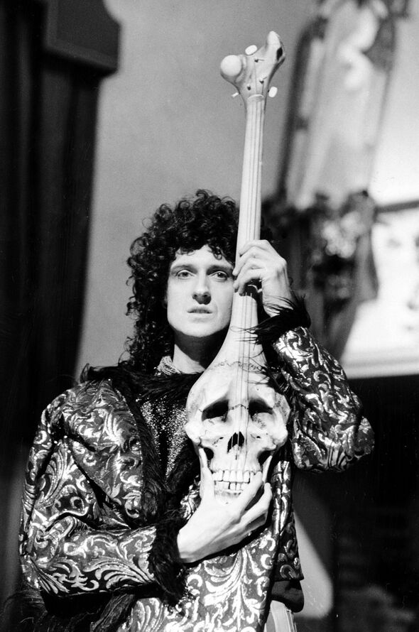 Brian May holds a skull and bones guitar aloft