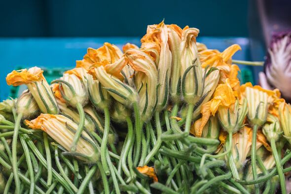 Fresh zucchini flowers displayed at a market stall