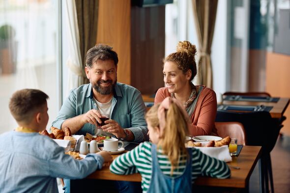 Happy family talking while having breakfast in a restaurant at the hotel.