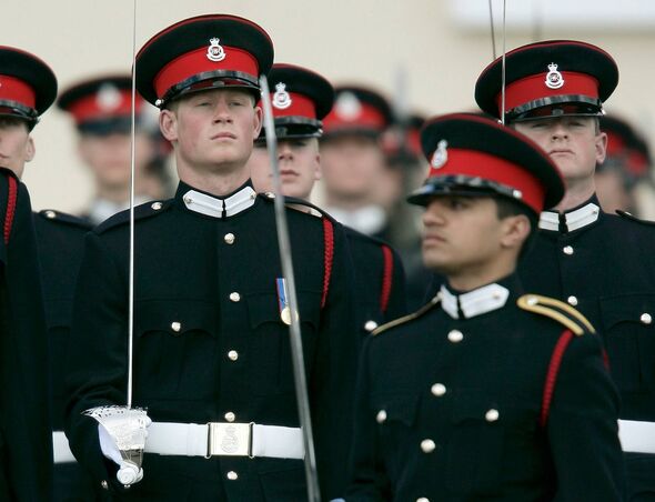 A group of military officers dressed in formal uniforms with hats adorned with red and black accents, standing in formation with