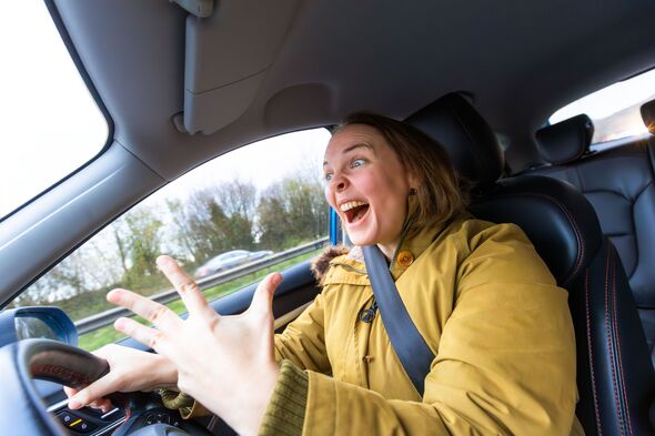 Angry young woman driver experiencing road rage while driving