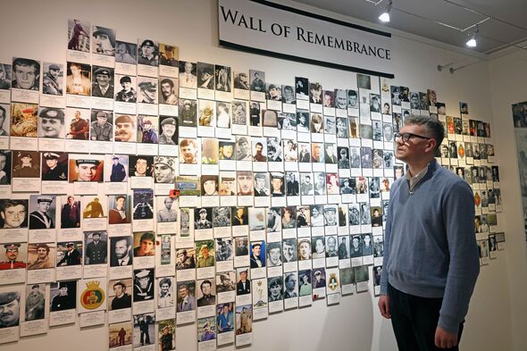 Adam Toms looks at the wall of photos