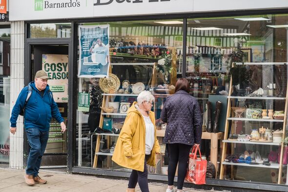 A person looks at a charity shop window display