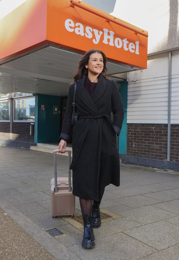 Hattie Carter rolling a suitcase outside of easyHotel London