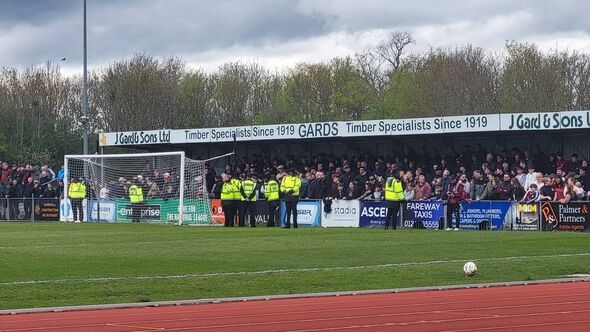 Security stewards line a covered terracing housing Chelmsford City supporters during their fixture against Enfield Town