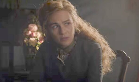 A woman with red hair sits and looks scared