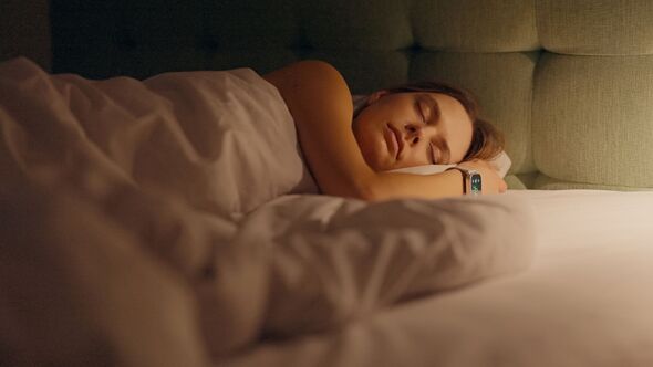 Woman sleeping in a bed at night. Digital hand watch showing time and tracking sleep quality