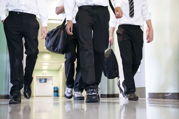 Low section of teenage boys walking through corridor on way to class, focus on legs and feet