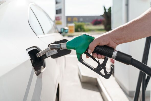 Man's hand holding green petrol pump and feeling car