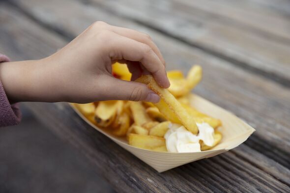 Close up of child dipping takeaway chips into a portion of mayonnaise
