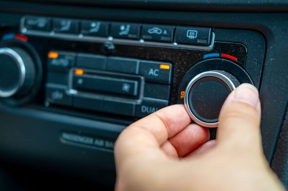 lose-up hand adjusting temperature dial car's climate control system, set 19C, with illuminated buttons for AC, AUTO, dual-zone settings, Climate comf