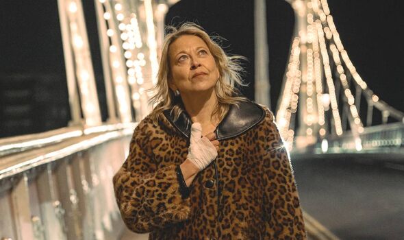 A woman with a bandaged hand walks along a lit up bridge