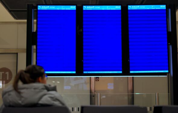 A woman sits in front of empty arrival boards at Terminal 1 of Berlin Brandenburg Airport in Schoenefeld