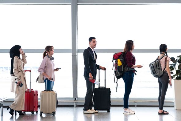 Row of travelers queue in the departure hall