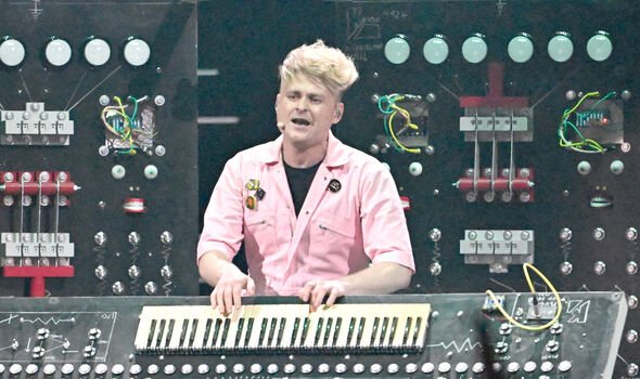A man in a pink shirt plays a keyboard