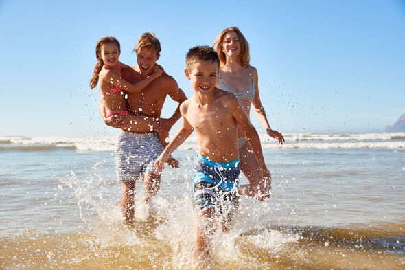Family On Summer Beach Vacation Run Out Of Sea