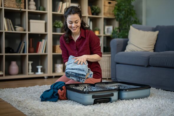 Woman packing suitcase for vacation trip on floor