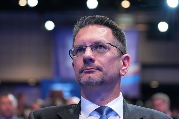 Steve Baker sits in conference audience