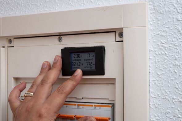 Hand monitoring electrical energy usage on smart meter display