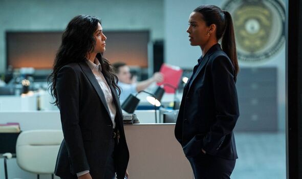 Two women in suits talking.