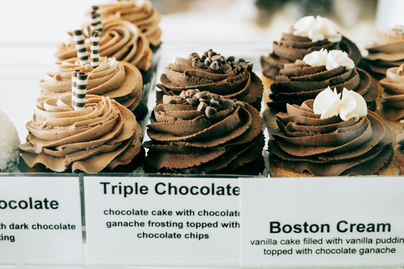Close view of chocolate cupcakes topped with layered frosting, chocolate chips, and decorative elements. Labels indicate triple chocolate and Boston c