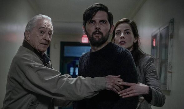 Two men and a woman standing in a hallway.