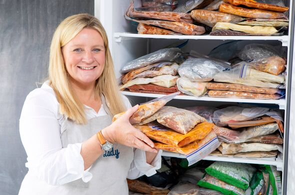 An individual, presumably a cook or a chef, is standing before a refrigerator, holding a tray containing a variety of packaged f