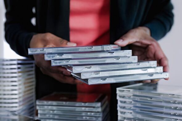 A woman holding a stack of CDs