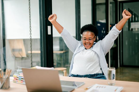 Excited young adult woman celebrating business success in office