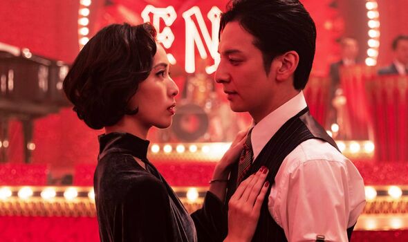 A man and woman dance together against a red stage