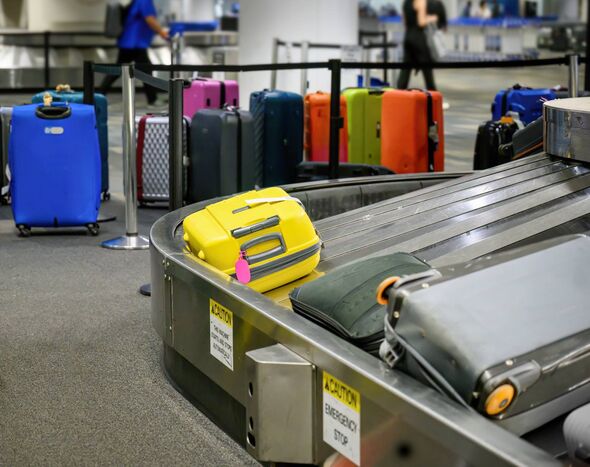 Suitcases on luggage conveyor belt in baggage claim at airport.