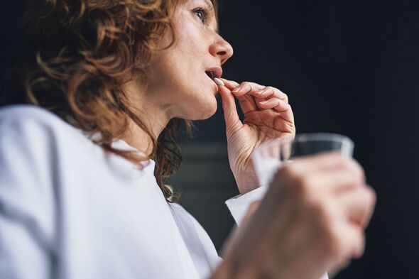 Woman taking pill with glass of water