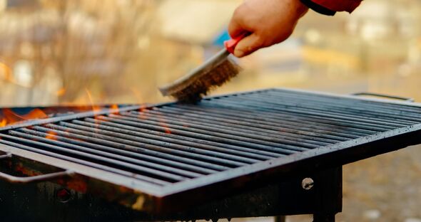 Chef cleaning grill grate with wire brush