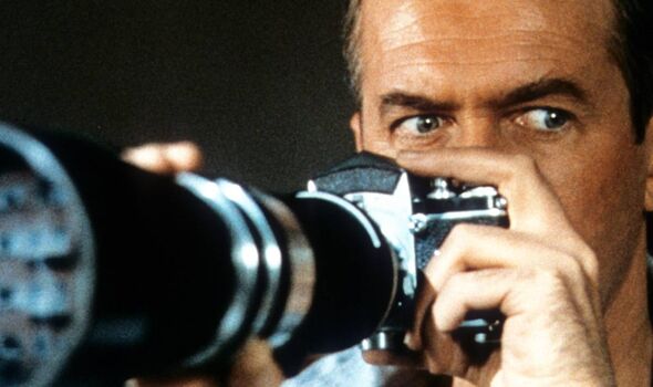 A man holds a long-lens camera up to his face