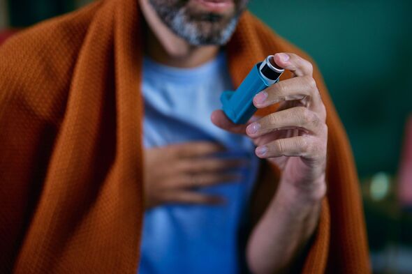 Man using asthma inhaler experiencing breathing difficulty