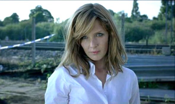 A woman in a white shirt stands in front of police tape