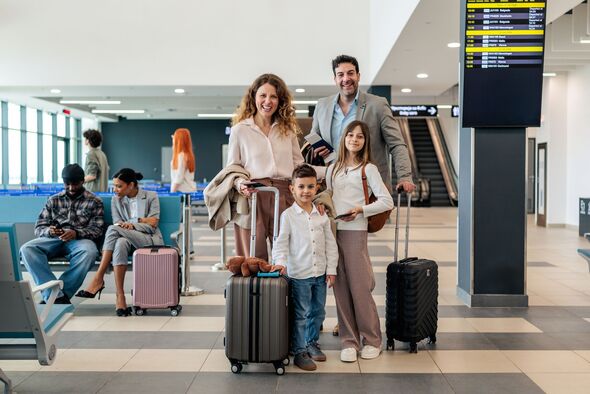 Portrait Of Happy Family With Children At Airport Before Flight