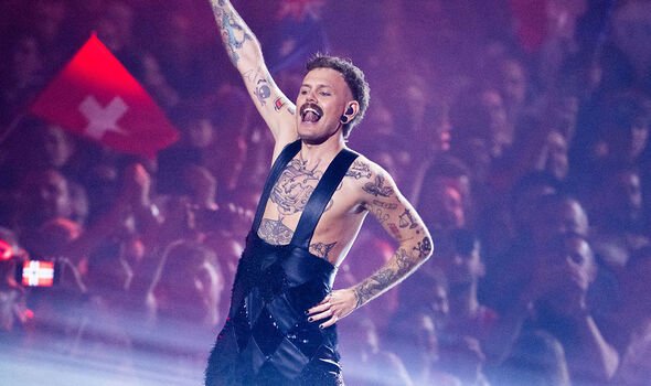 A man raises his arm as he performs on stage