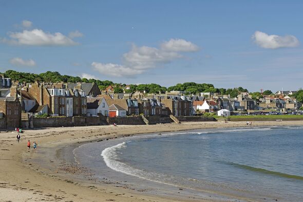 Houses along a beach with walkers by the sea under a blue sky on a sunny day, North Berwick, Scotland, United Kingdom, Europe