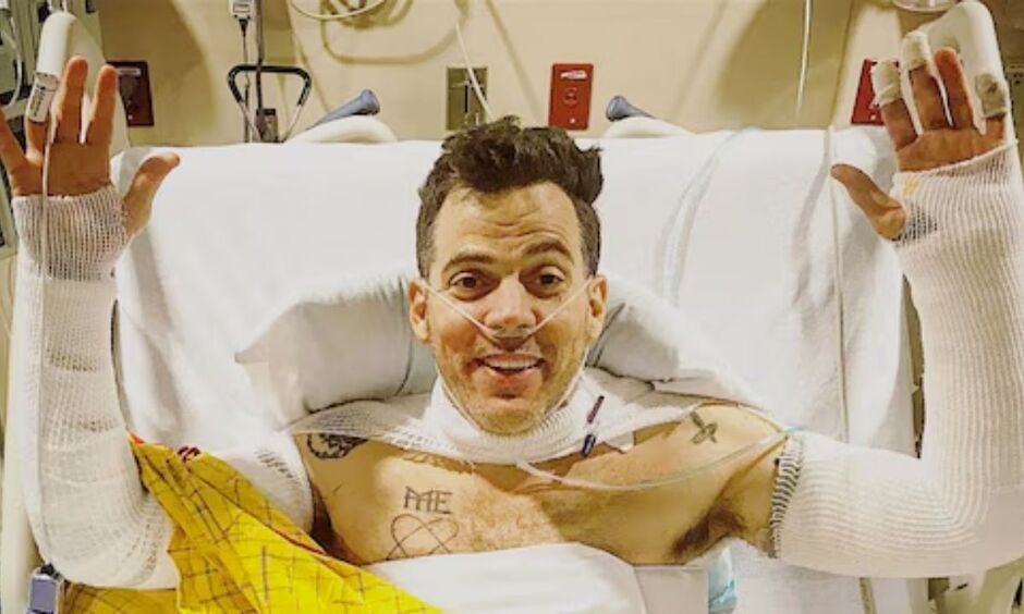 Steve-O in a hospital bed with both arms in casts