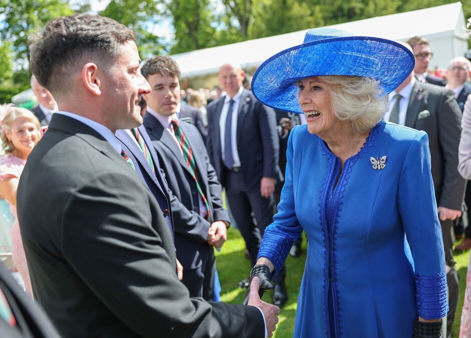 Queen Camilla smiles as she shakes hands with guests
